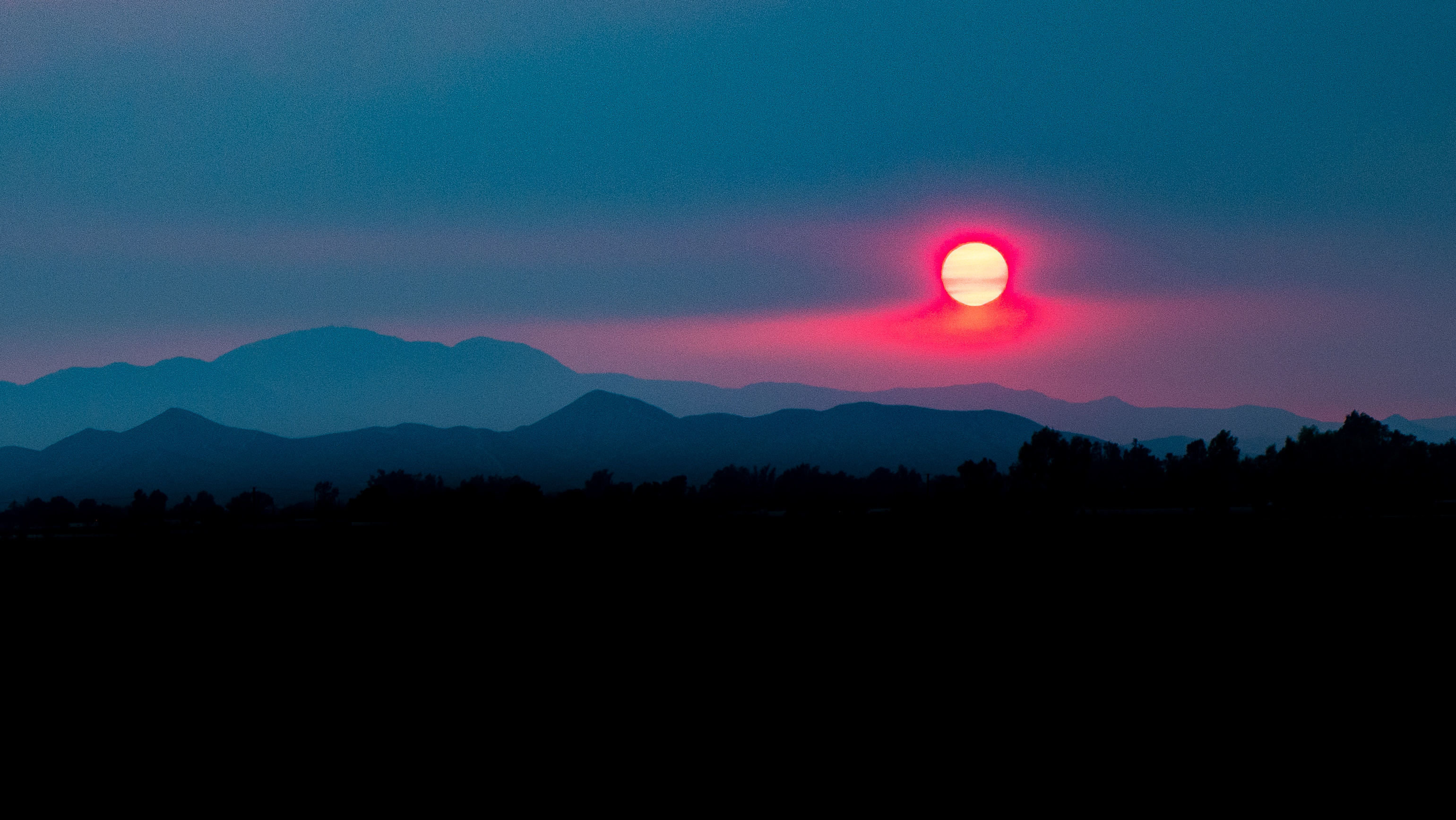 Wildfire smoke creating a hazy orange sky at sunset